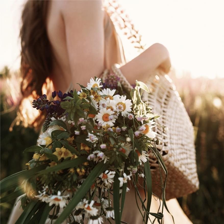 Sunlit wildflowers gathered in a woven bag