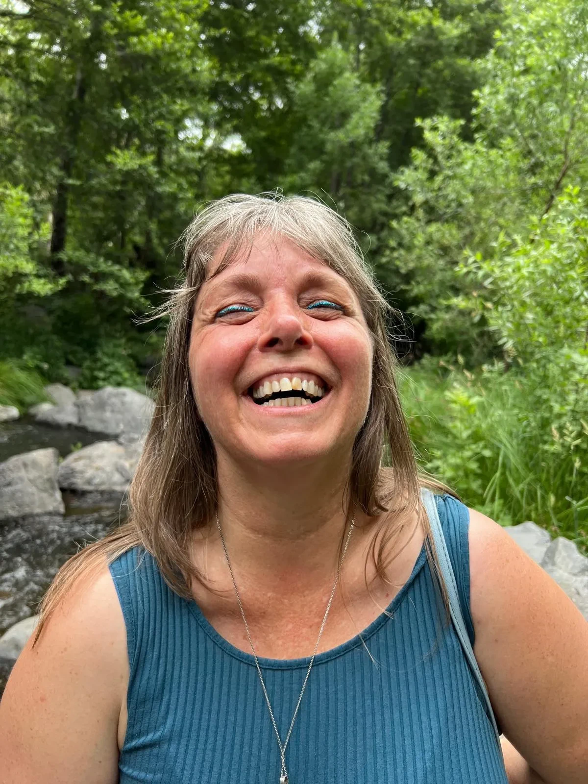 Raejean laughing beside a creek in the woods